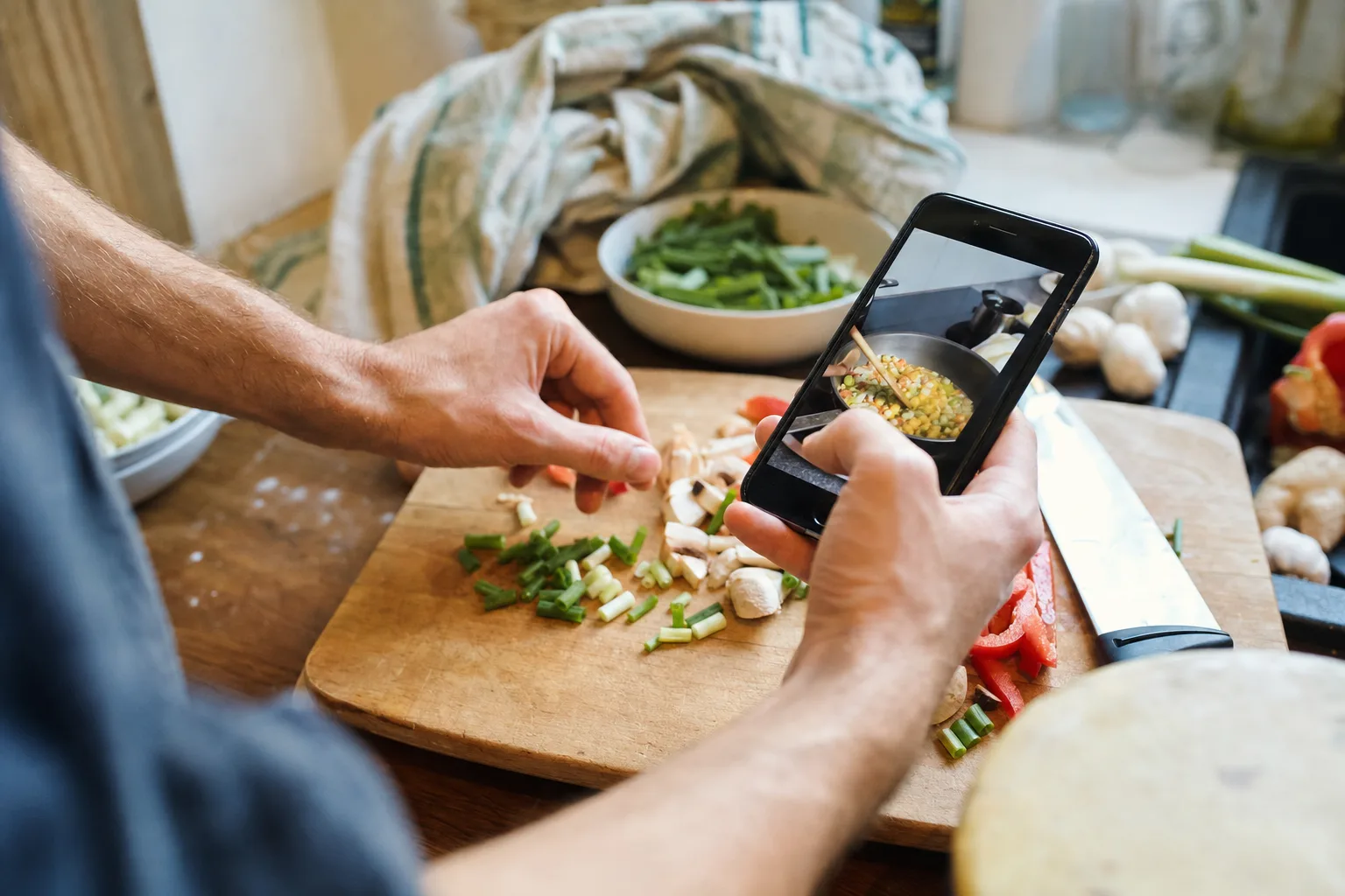 Home cook saving a recipe from a phone while preparing vegetables